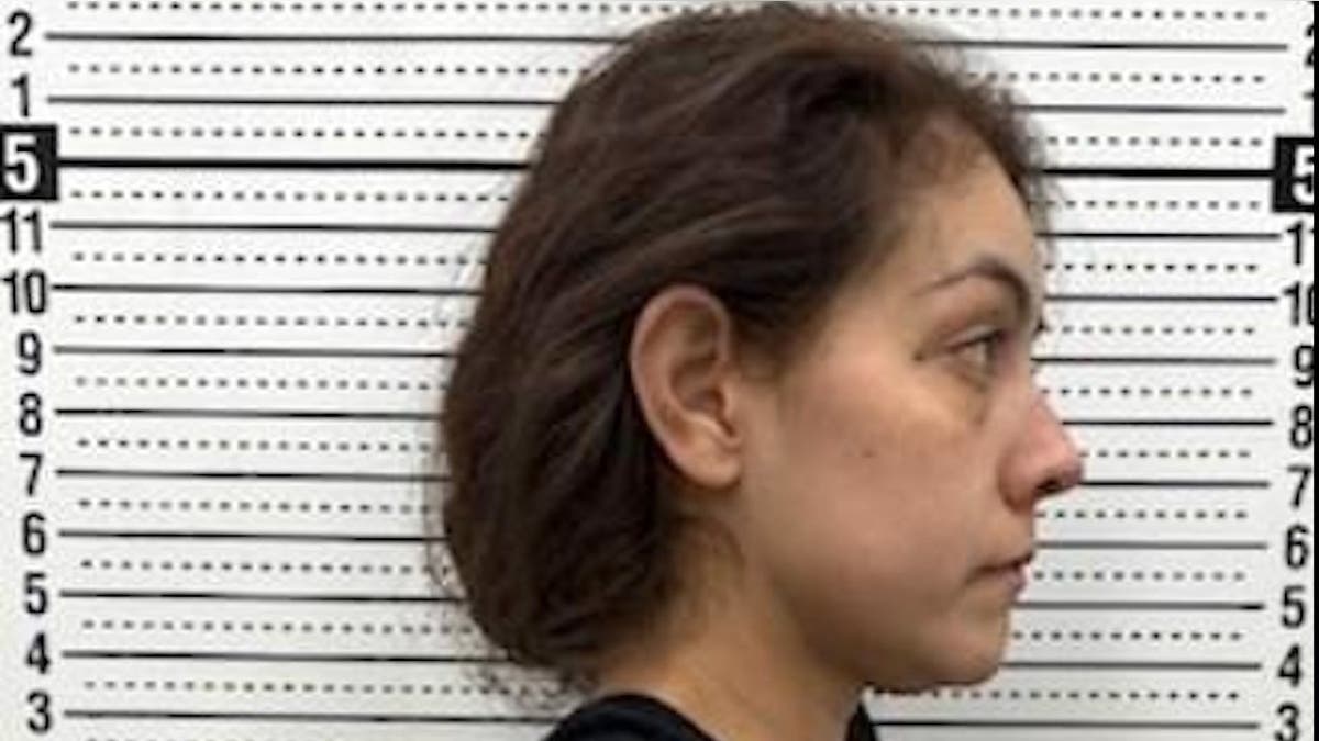 a woman stands next to a police measurement backboard showing her heigh as 5-feet, 2 1/2 inches