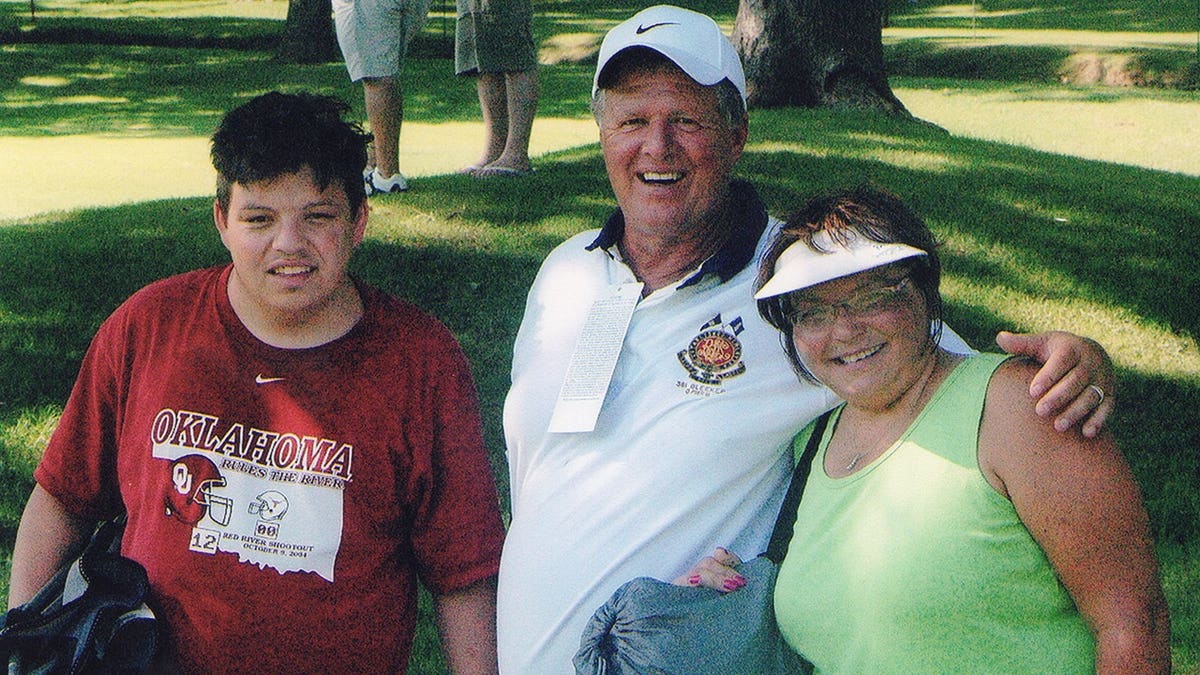 Jeff Walton and Deb Proctor smiling together in a gold field with a young man.