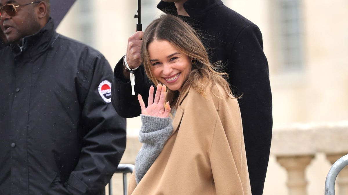 Emilia Clarke waves at fashion week