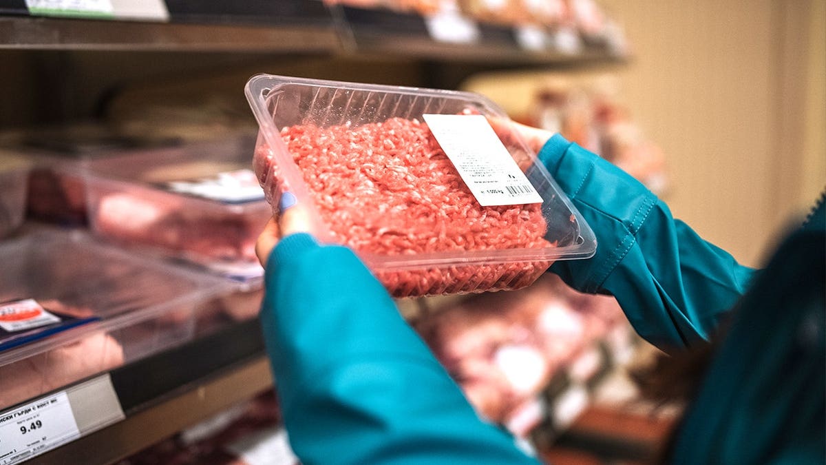 Woman holding ground beef in grocery store