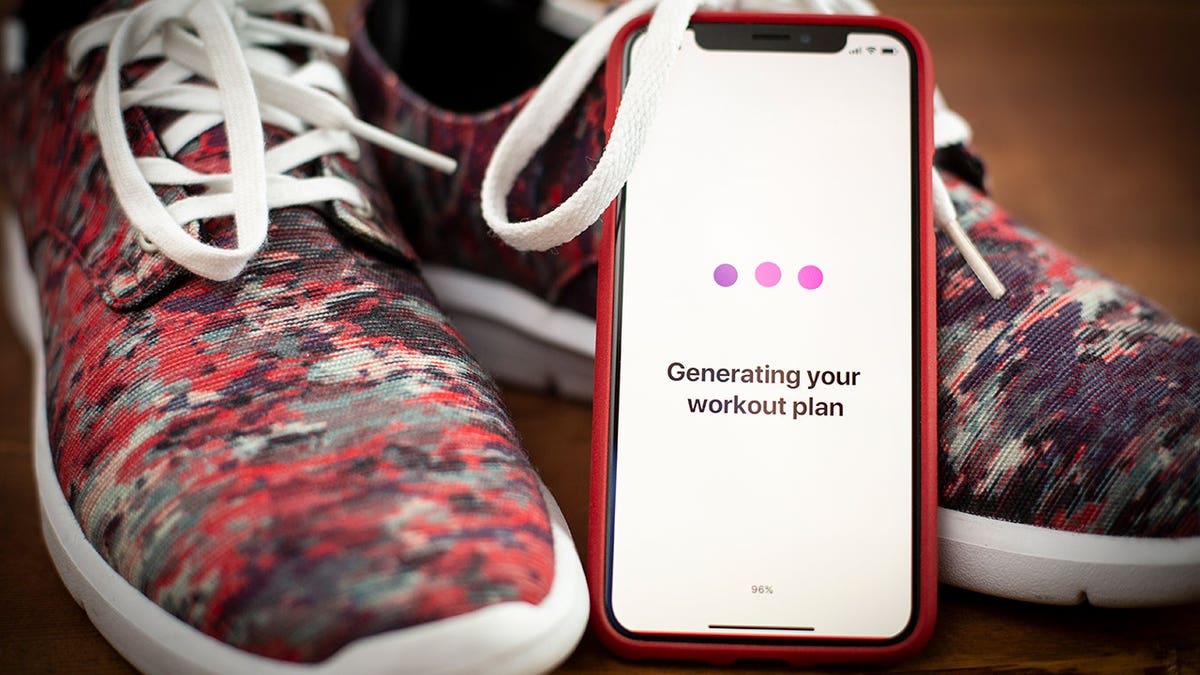 A smartphone leaning on workout shoes.