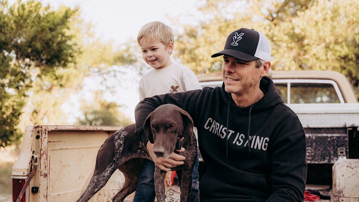 Granger Smith sitting in his truck with his son Maverick and their dog.