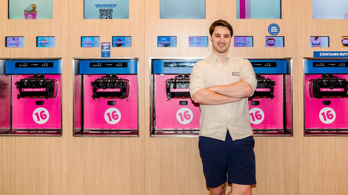 Neil Hershman stands in front of 16 Handles soft serve machines in a store.