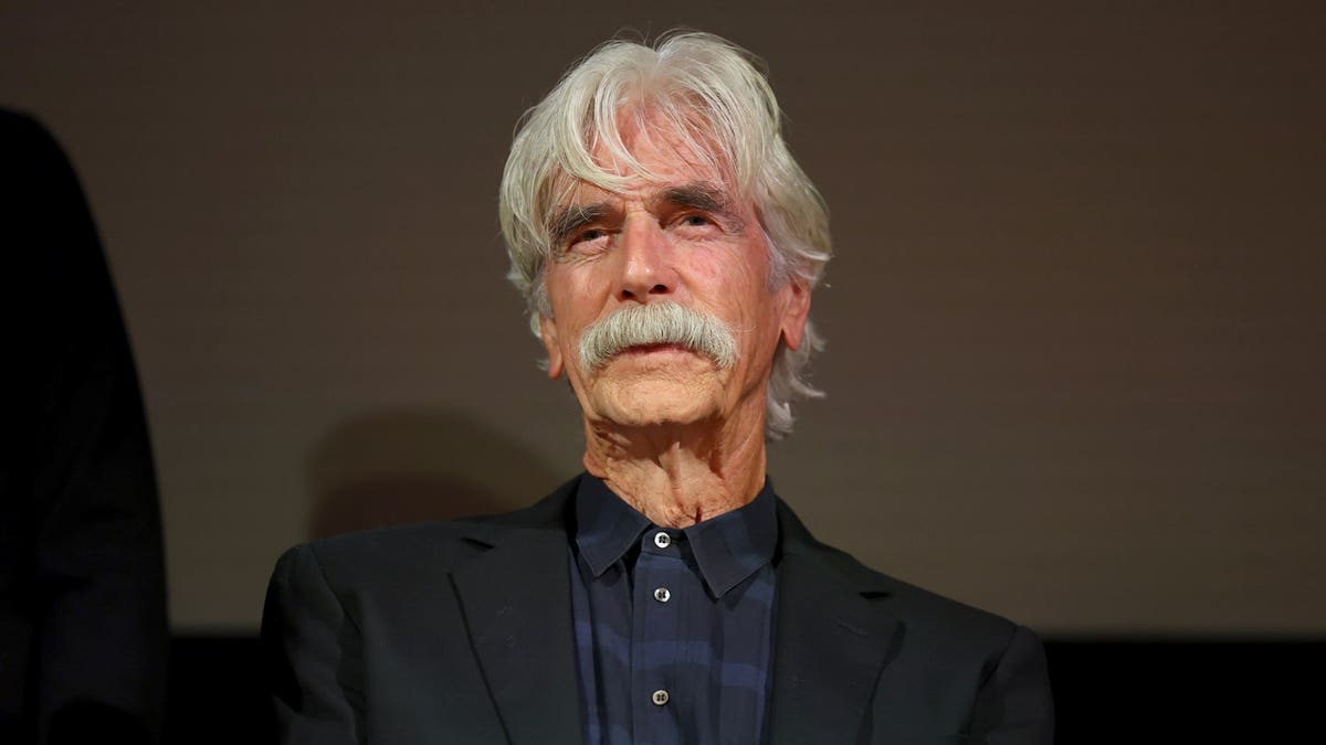 Sam Elliott sits on stage during a panel