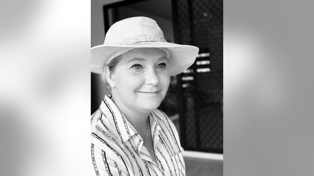 A black and white photo of Virginia Roberts Giuffre wearing a white striped shirt and a white fedora.