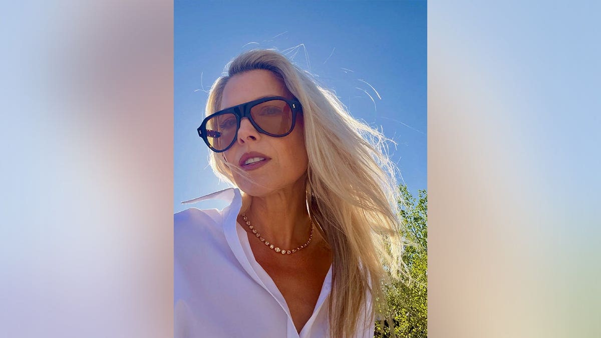 Ali Larter posing in dark sunglasses and a white shirt in May 2026.
