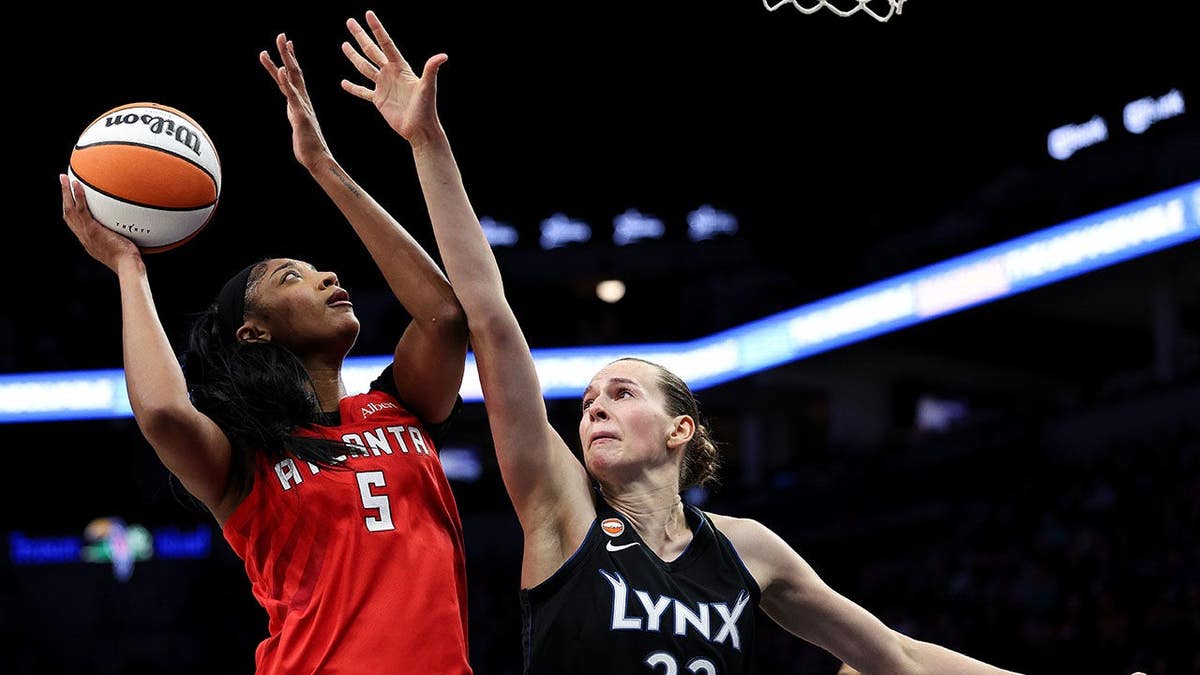 Angel Reese arremessando uma bola de basquete enquanto Emma Cechova defende no Target Center