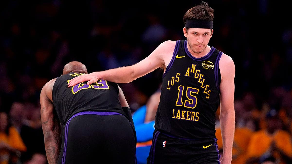 Los Angeles Lakers defender  Austin Reaves pats guardant  LeBron James connected  the backmost  during a game.