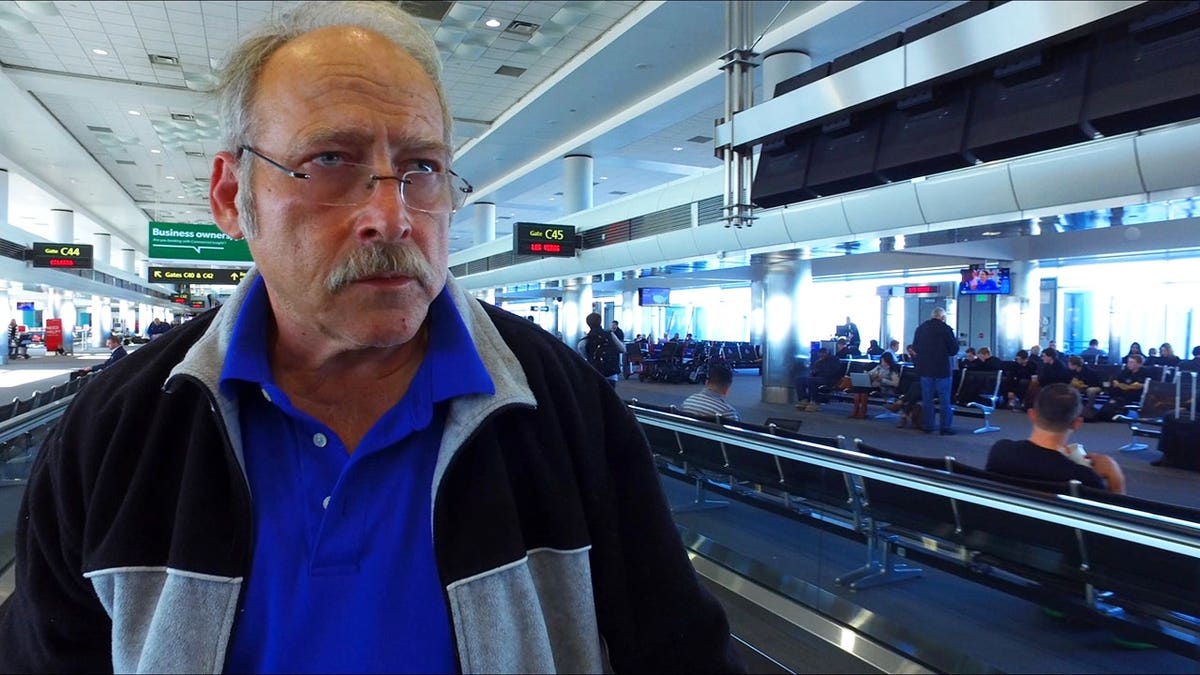 Benjaman walking through Denver Airport terminal.