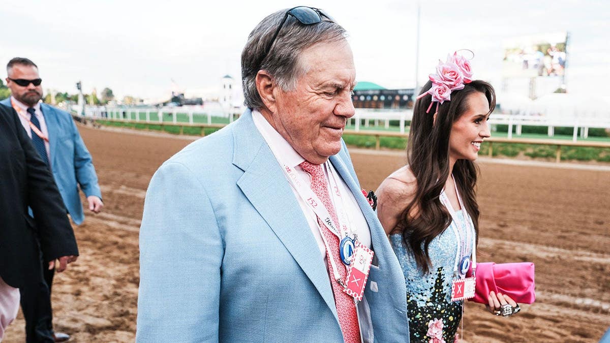 Bill Belichick and girlfriend Jordon Hudson standing on dirt track at Churchill Downs