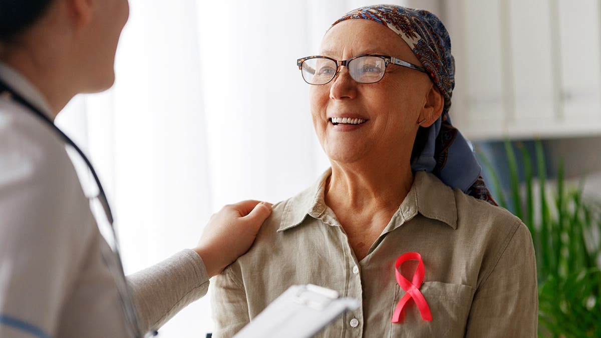 A cancer survivor smiles at a doctor in a doctor's office.