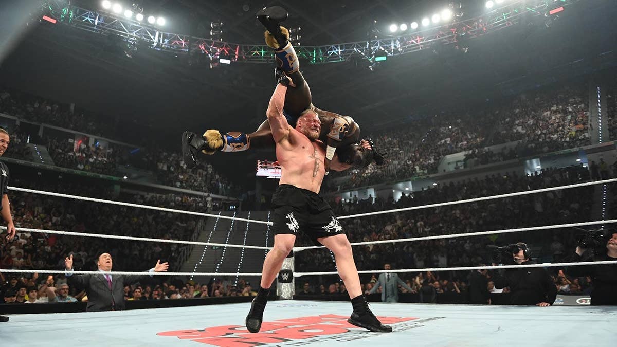 Brock Lesnar performing an F5 wrestling move on Oba Femi in a ring.