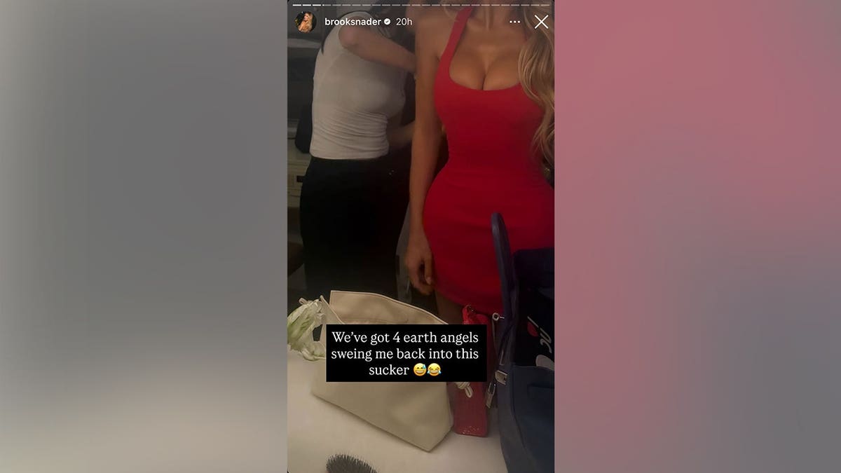 Nader in a red dress with someone behind her sewing her into her dress in May 2026.
