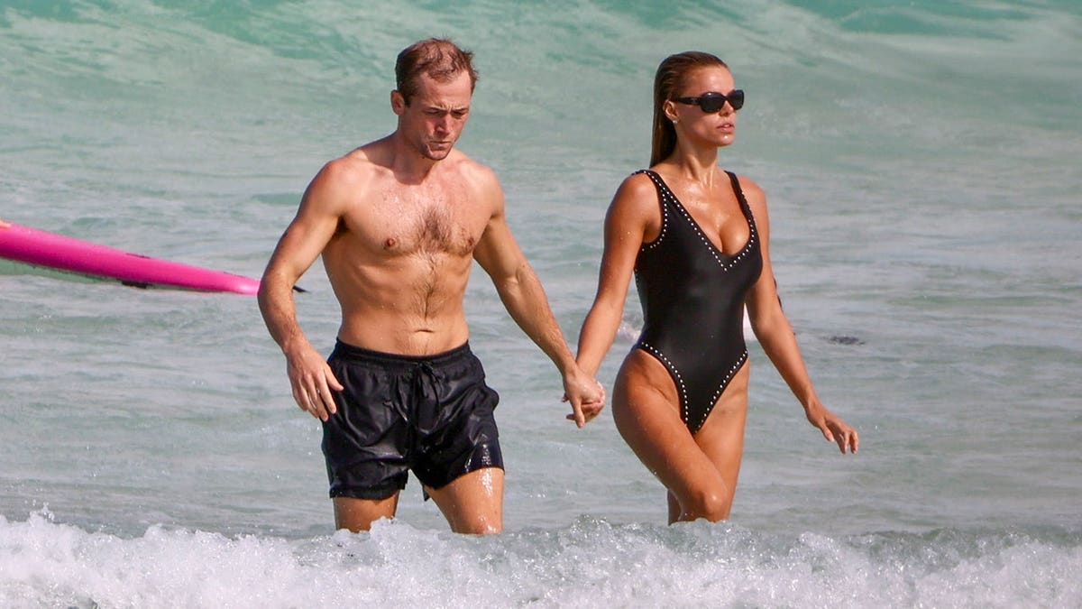 Brooks Nader and Taron Egerton wading in shallow water at Bondi Beach