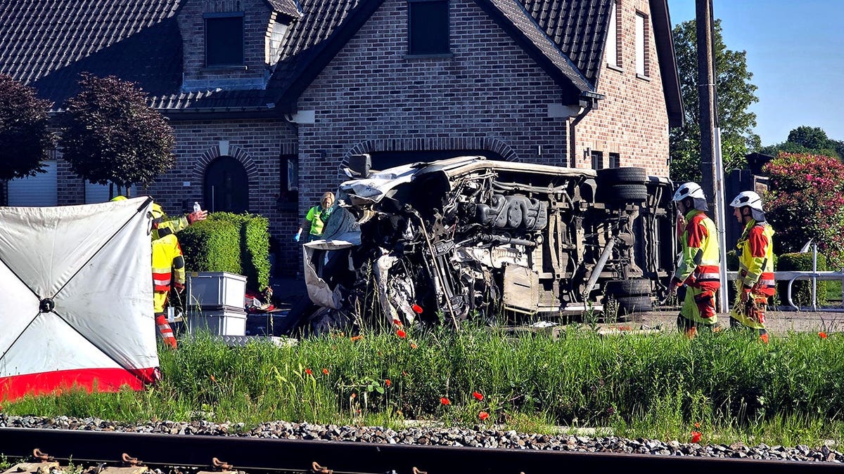 Rescue workers attending to crash site between train and vehicle in Buggenhout Belgium