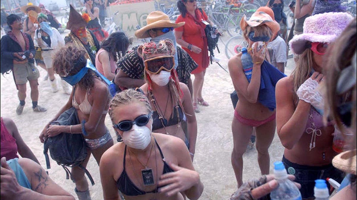 Burners in bikinis covering their faces during a dust storm at Burning Man festival