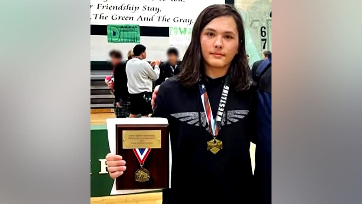 Cain Clark holding a wrestling plaque