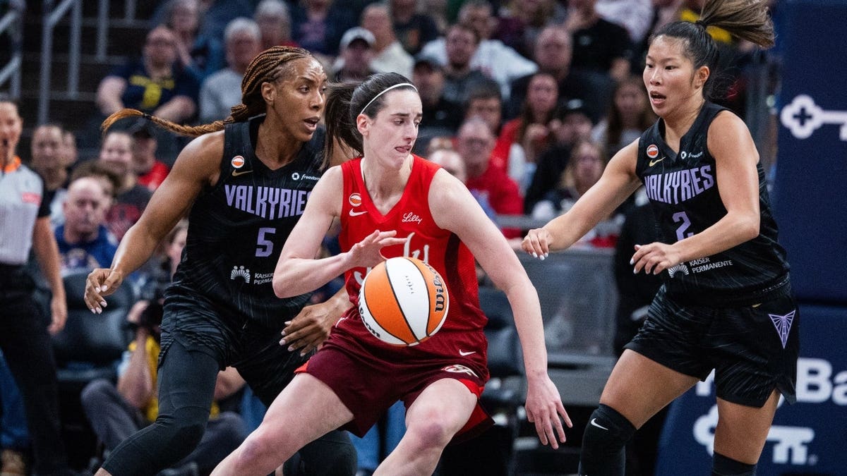 Indiana Fever guard Caitlin Clark dribbling basketball defended by Golden State Valkyries players at Gainbridge Fieldhouse