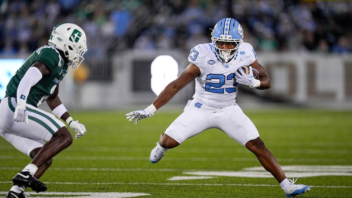 North Carolina Tar Heels running back Charleston French correndo com a bola defendida pelo zagueiro Treyveon McGee do Charlotte 49ers
