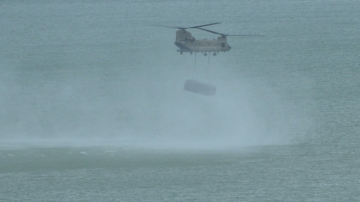 Chinook helicopter drops bridge sections in water