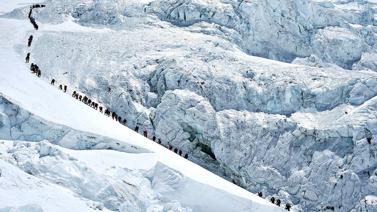 Climbers walking in a long queue ascending Mount Everest in Nepal