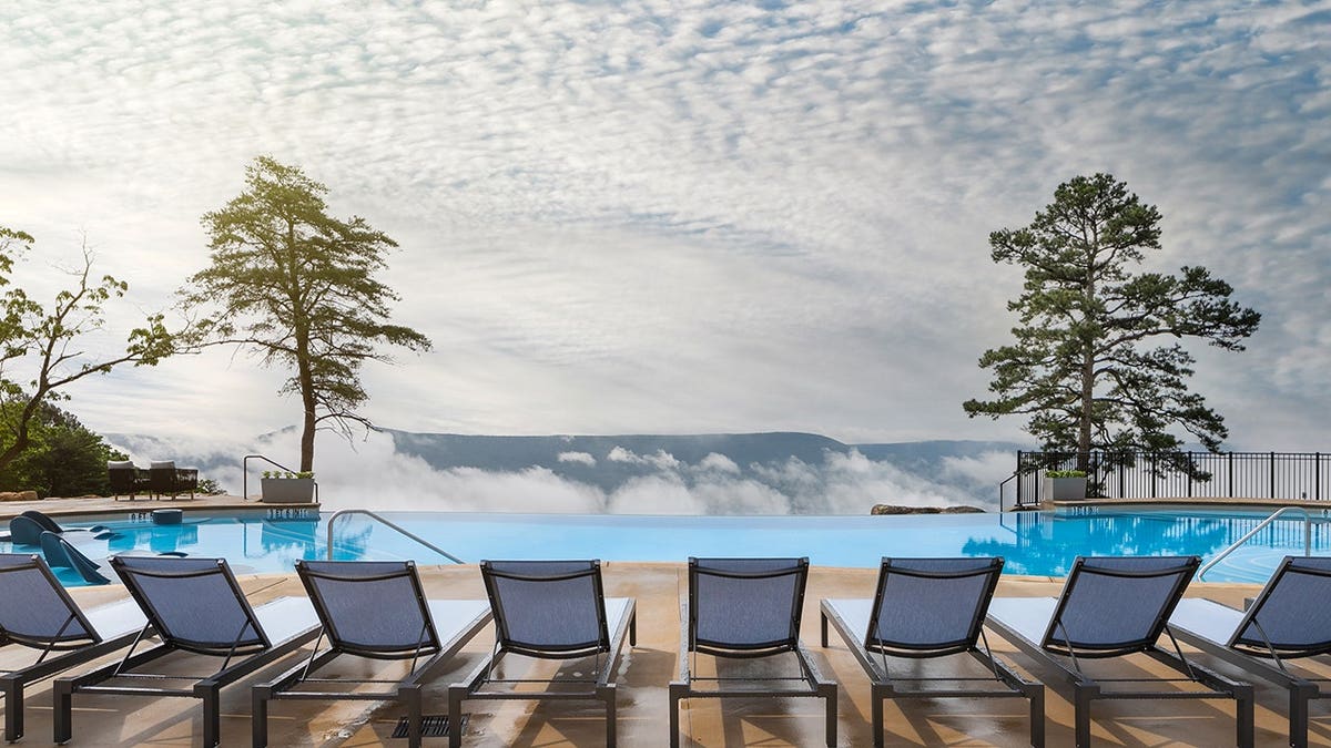 pool chairs lined up behind cliffside infinity swimming pool