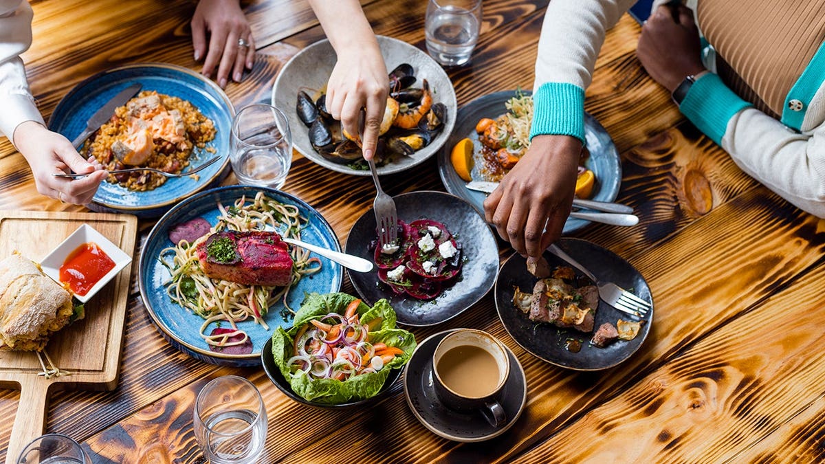 Bird's eye view of wooden table with communal dining and fork spearing beets on a plate