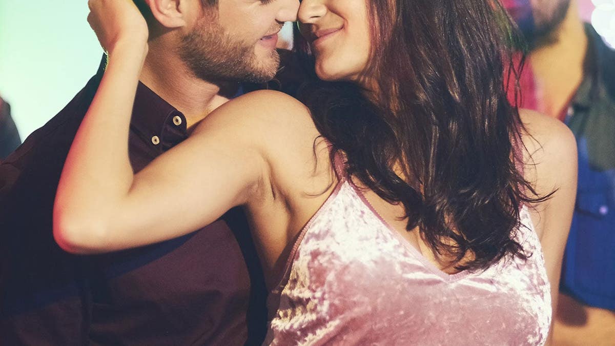 A young couple dancing closely on a crowded nightclub dance floor