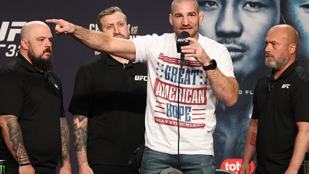 Sean Strickland standing on stage at UFC 328 press conference in Newark, New Jersey
