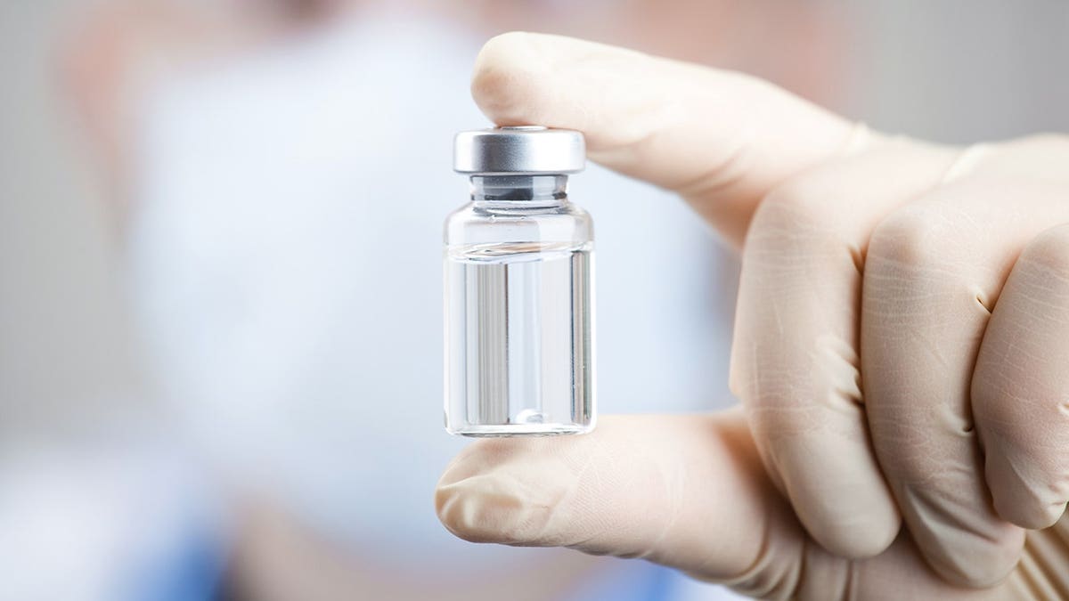 A doc holding a vial and syringe preparing for injection