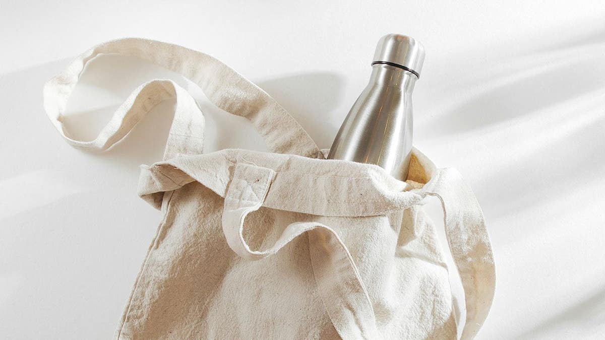 Natural color eco bag with reusable metal water bottle on flat surface