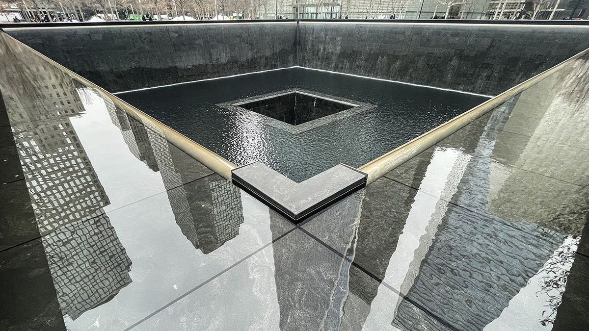 Freedom Tower reflected in the Reflecting Pool at the 9/11 Memorial in New York City.