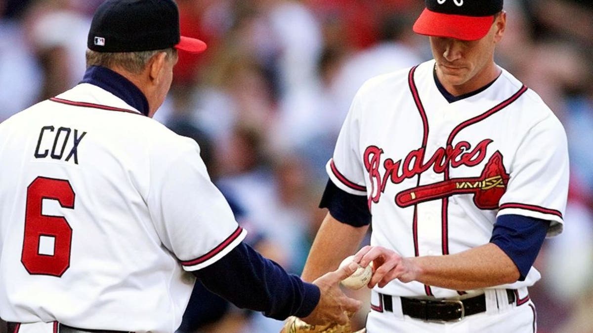Starting pitcher Tom Glavine (R) of the Atlanta Braves hands the ball to manager Bobby Cox after being taken out of the game in the sixth inning against the San Diego Padres during game six of the National League Championship Series 14 October at Turner Field in Atlanta, GA. The Padres lead the best-of-seven series 3-2.