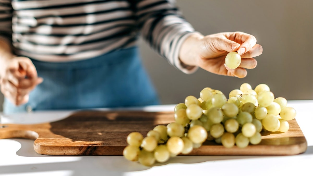 Una mujer comiendo uvas