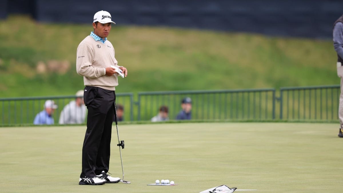 Hideki Matsuyama prepares to putt on the practice greens at the Aronimink Golf Club during a practice round for the 2026 PGA Championship.
