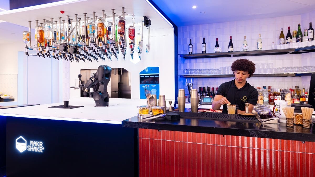 A bartender making drinks next to a robot
