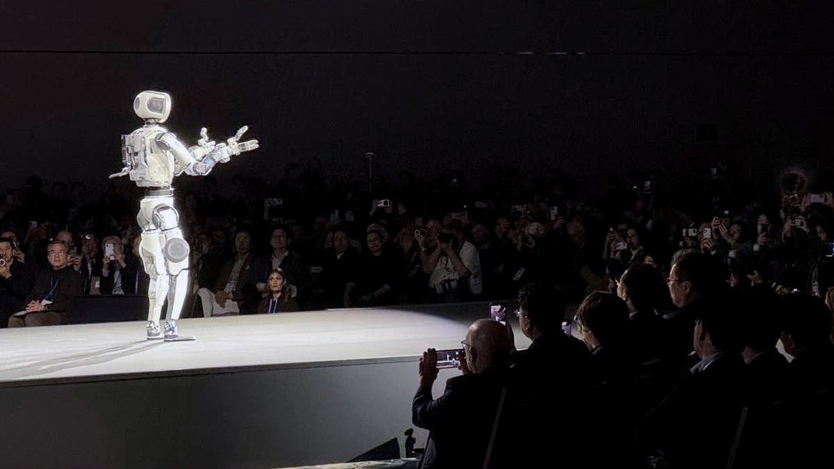 A Hyundai robot stands before a crowd.