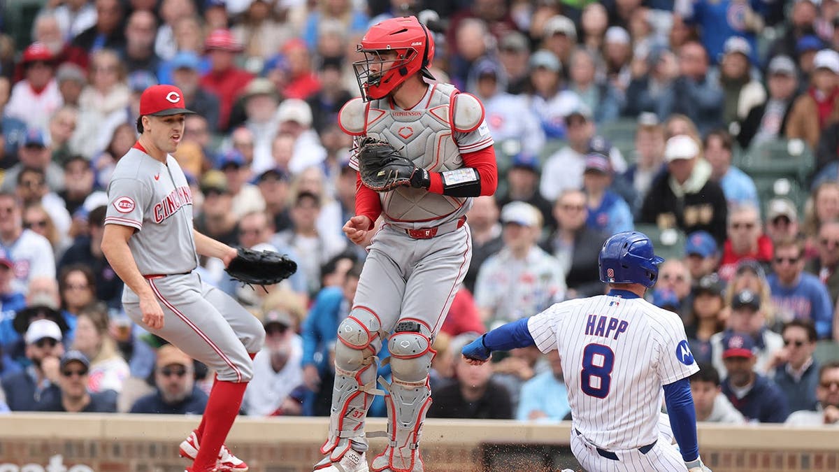 Ian Happ scoring a run past Tyler Stephenson at Wrigley Field