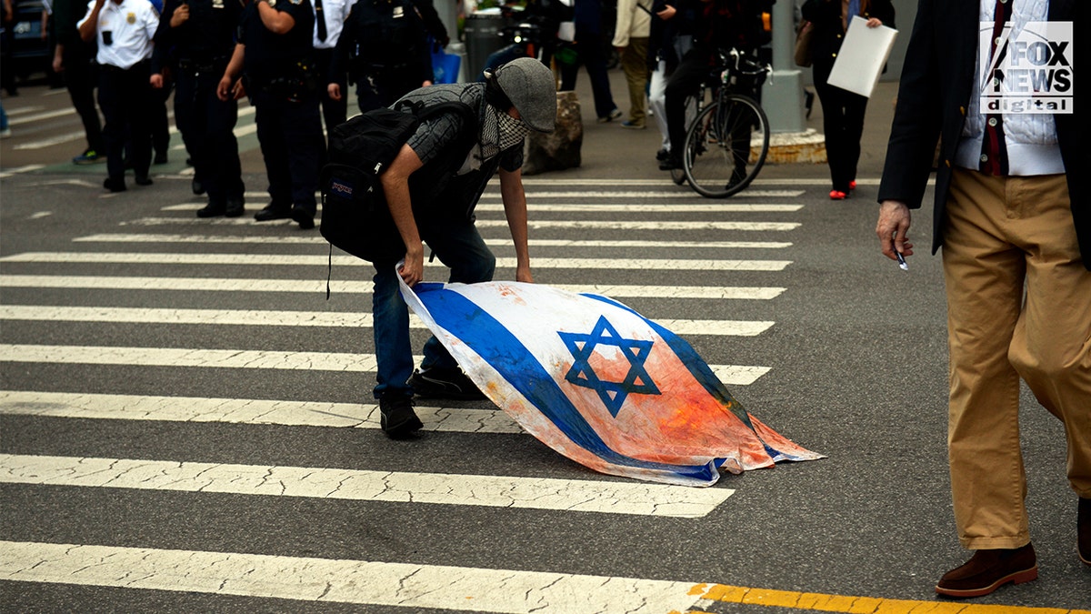 Demonstrator handling an Israeli flag stained with red in a street protest in Manhattan