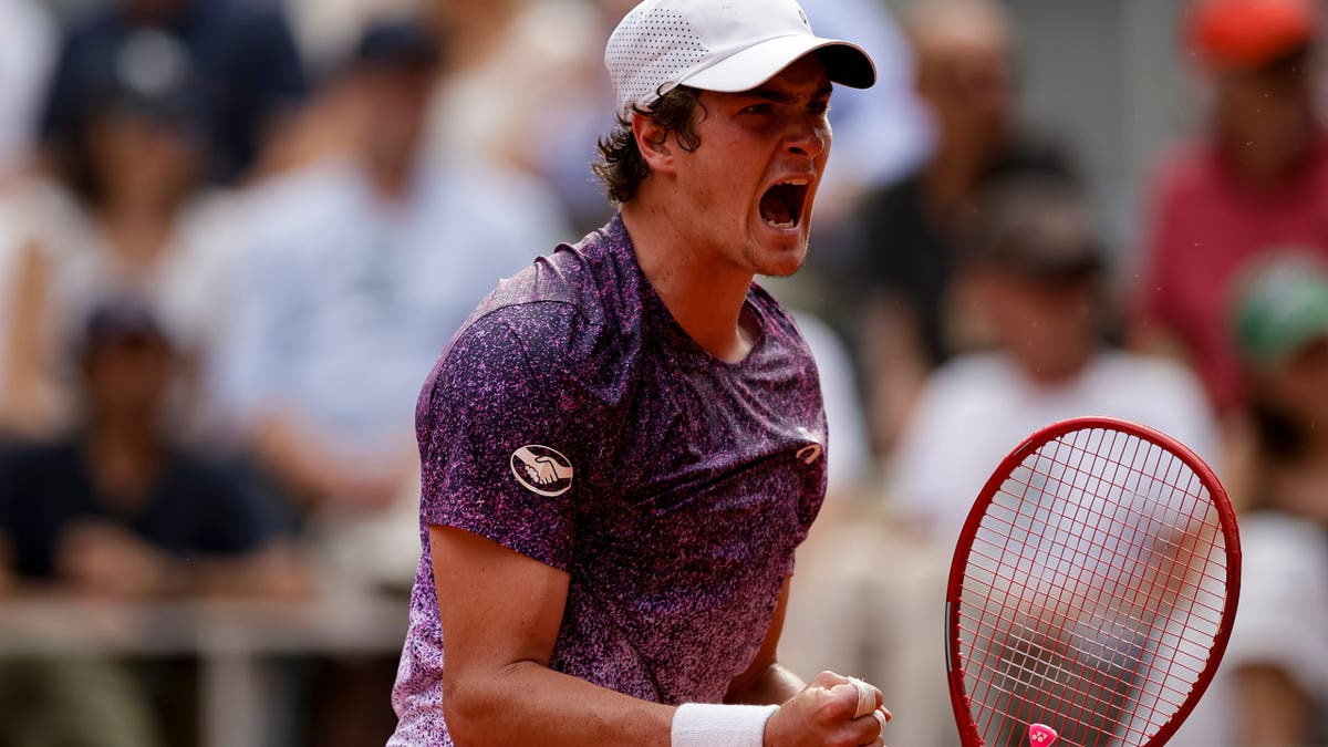 João Fonseca celebrating winning a match point against Novak Djokovic at the French Open in Paris