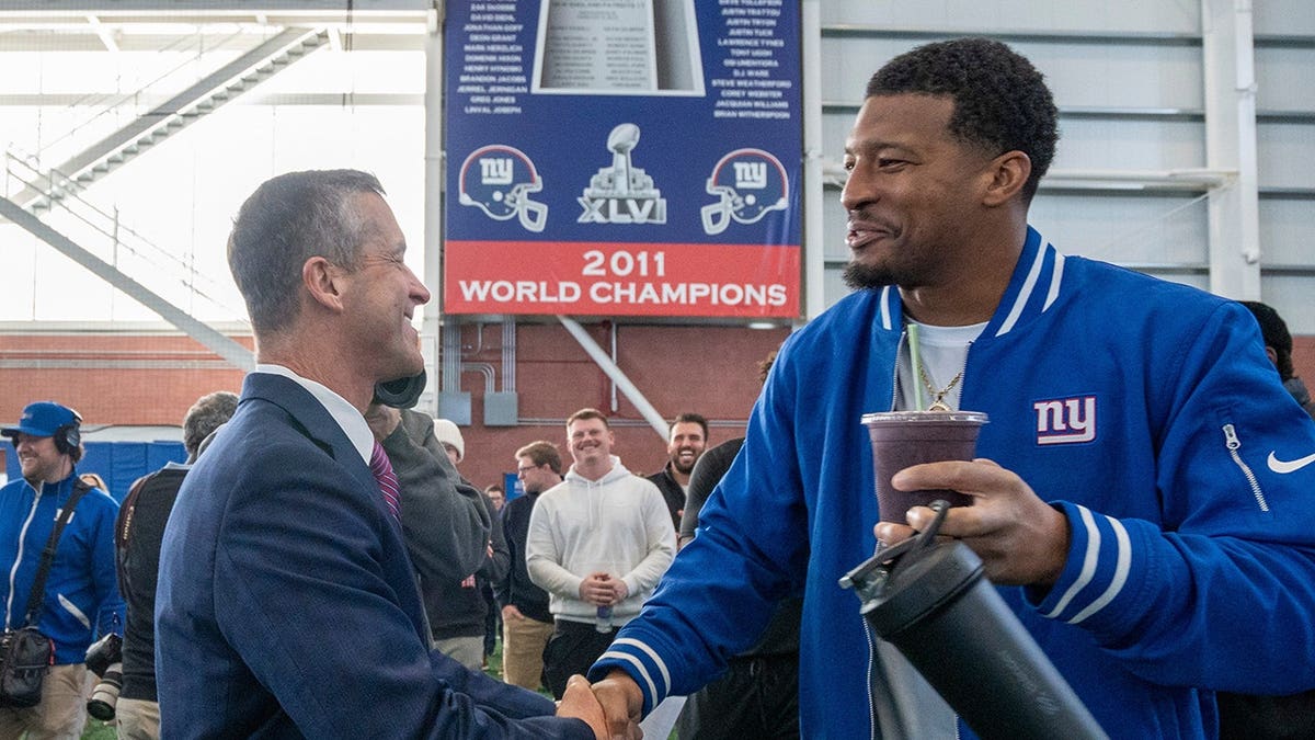 New Head Coach John Harbaugh shaking hands with New York Giants backmost   Jameis Winston astatine  a property   conference