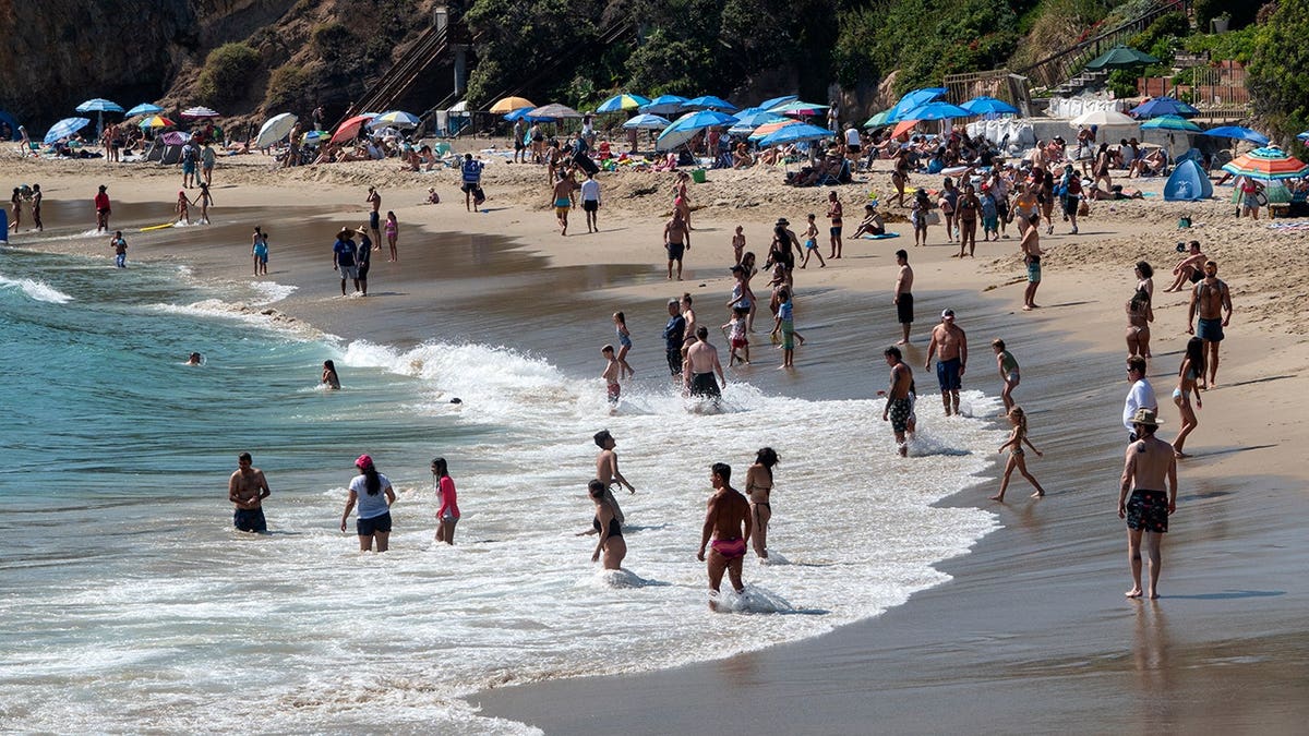 People walking and sitting on Crescent Bay Beach in Laguna Beach California