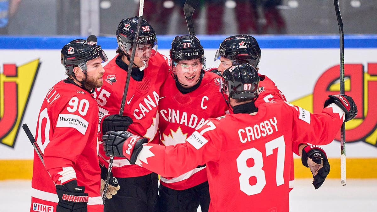 Macklin Celebrini scoring a goal with teammates Mark Scheifele, Ryan O'Reilly, Denton Mateychuk, and Sidney Crosby celebrating on ice