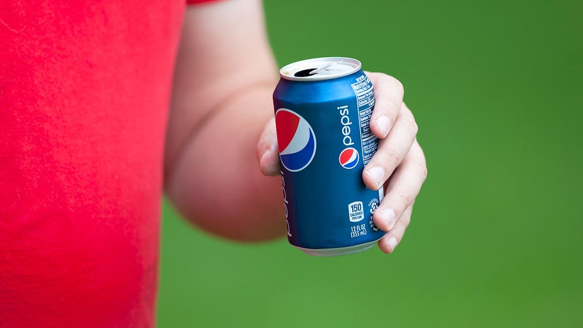 A woman holds a can of Pepsi.
