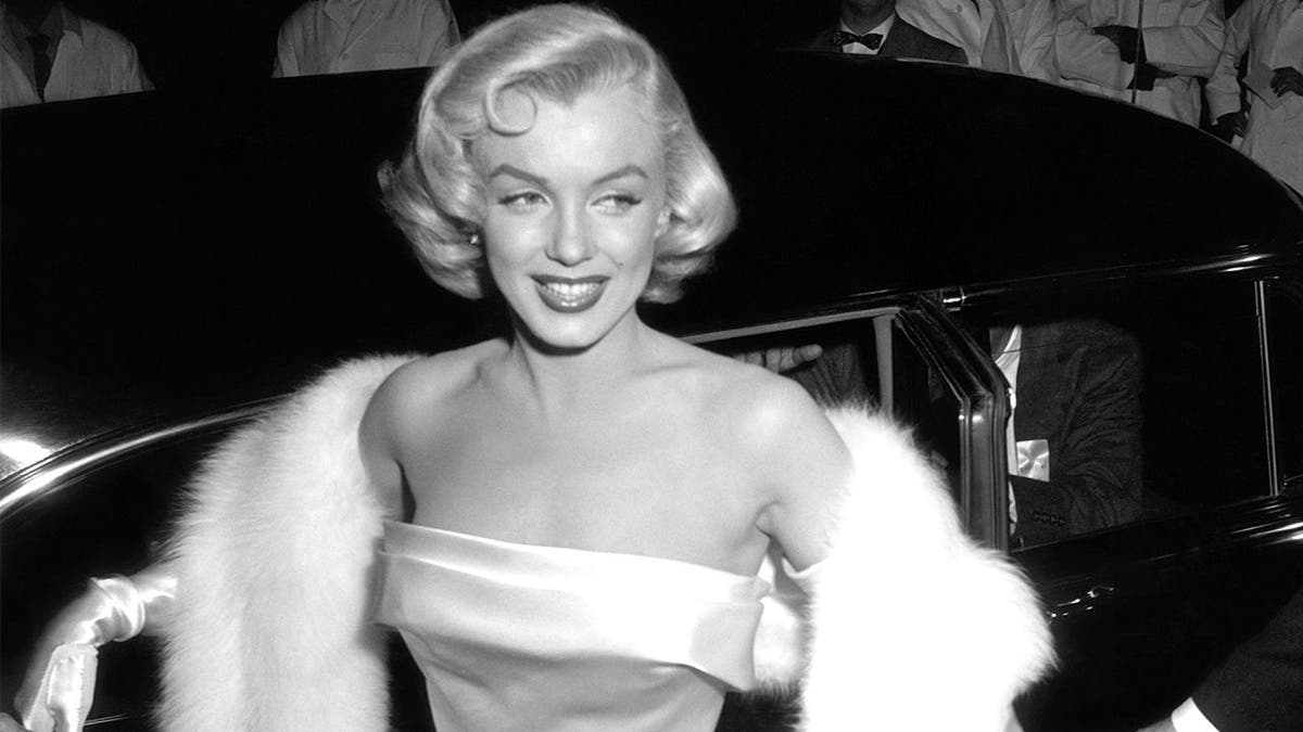 Marilyn Monroe arrives at film premiere in glamorous evening attire.