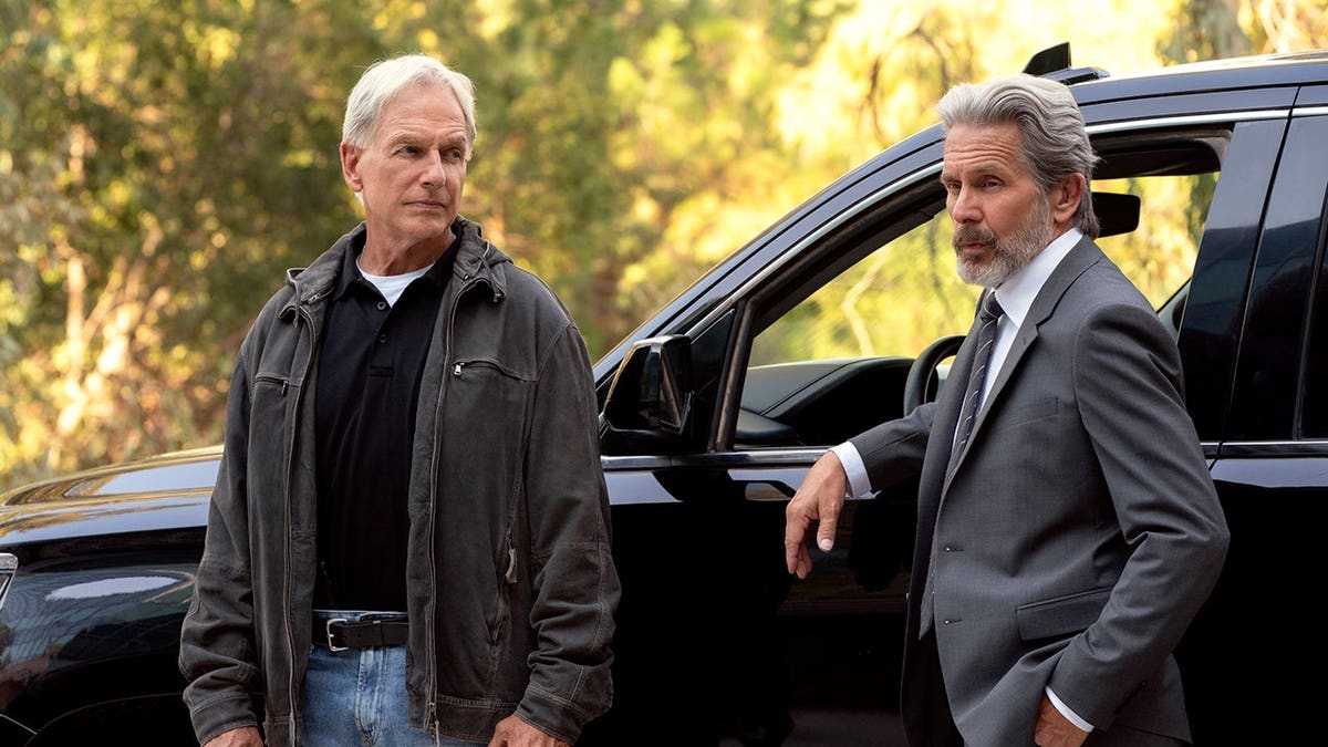 Mark Harmon and Gary Cole standing together on a set.