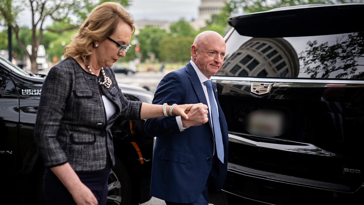 Mark y Gabby Giffords caminan de la mano hacia un todoterreno negro en Washington.
