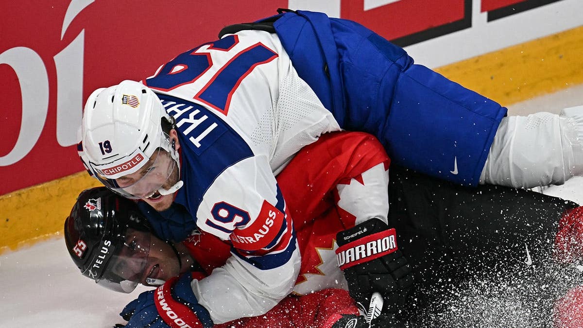 O atacante canadense Mark Scheifele e o atacante americano Matthew Tkachuk competindo pelo disco na pista de gelo.