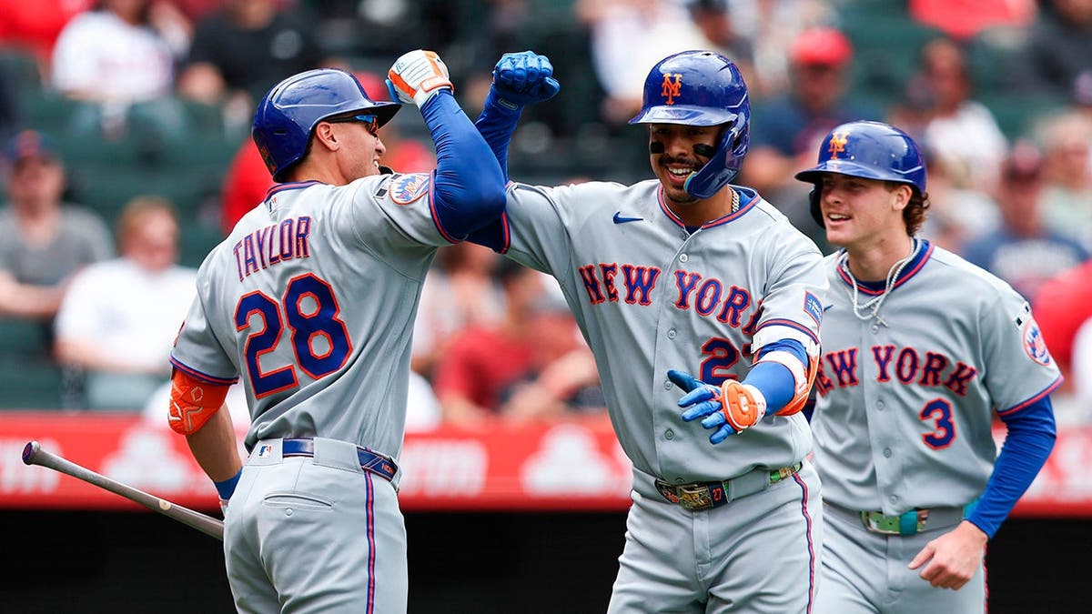 New York Mets' Mark Vientos celebrating with Tyrone Taylor and Carson Benge reacting on baseball field