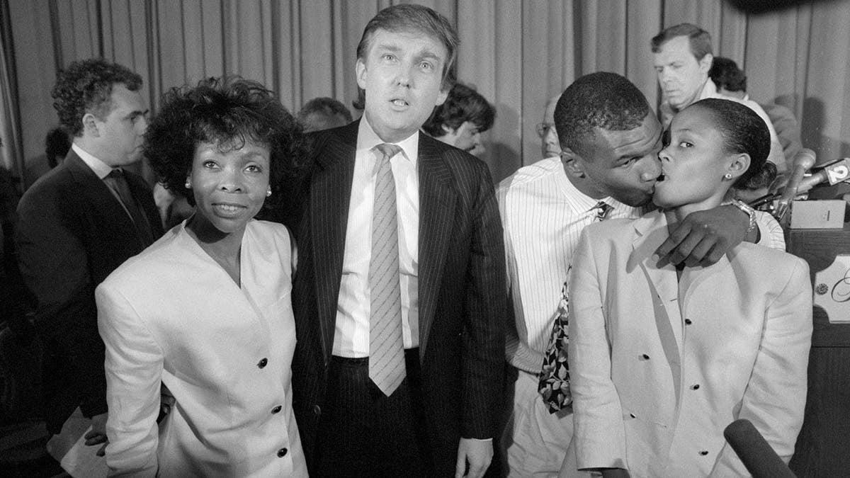Mike Tyson kisses wife Robin Givens while Donald Trump and Ruth Roper talk to media